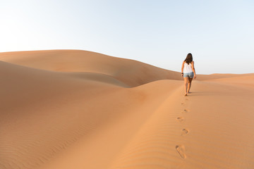 Beautiful woman hiking on giant sand dunes.