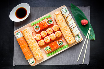Sushi rolls, soy sauce, ginger and chopsticks on a black background. Top view. Flat lay. Traditional natural food