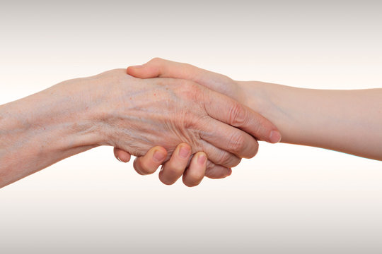 Handshake between an old person with a wrinkled hand and a kid, isolated on white background