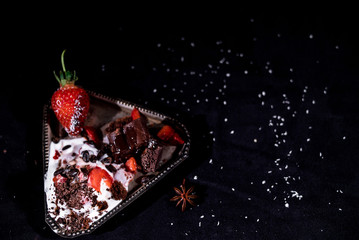 White icecream with chocolate and strawberry on the black background