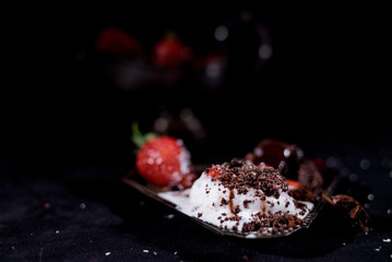 White icecream with chocolate and strawberry on the black background