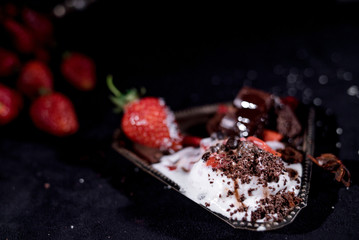 White icecream with chocolate and strawberry on the black background