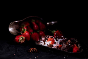 White icecream with chocolate and strawberry on the black background