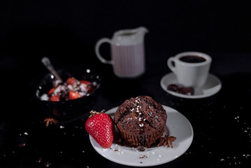 Coffee with chocolate muffin on a black background with strawberry and icecream with coconut chips