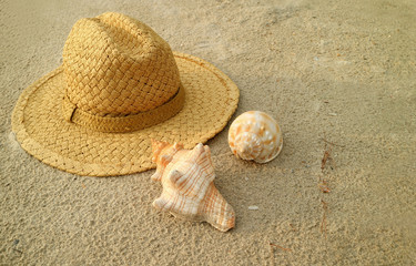 Natural brown straw hat with beautiful natural seashells on the sand beach of Thailand  