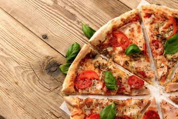 Hot and delicious pizza with salami tomatoes cheese and mushrooms ready to eat  on a wooden background. Top view.