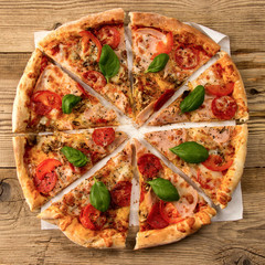Hot and delicious pizza with salami tomatoes cheese and mushrooms ready to eat  on a wooden background. Top view.