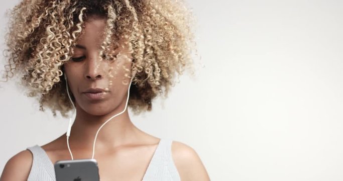 portrait of beauty mixed race woman with afro hair and freckles with earphones and smartphone