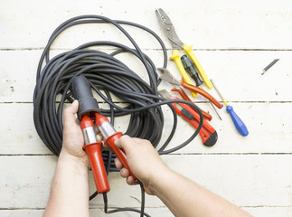 Electrical equipment, tools, cables and accessories used by an electrician on a wooden surface.