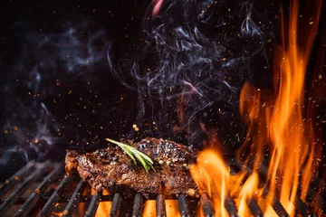 Foto auf Acrylglas Grill / Barbecue Rindersteaks auf dem Grill mit Flammen
