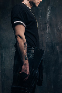 Unrecognizable outlaw person with sniper rifle closeup studio shoot. Armed white gangster man with weapon on dark background. Outlaw, ghetto, murderer, robbery concept