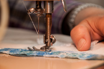 Sewing machine, sewing process, women's hands holding a cloth to sew, connect with another piece of cloth