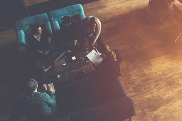 Business group researching new plan. Team meeting on the couch. Big open space office. Five people. Top view