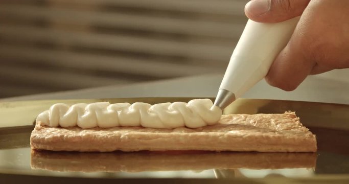 black chef put crem on puff pastry from pastry bag