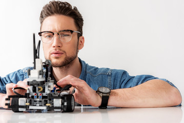 Serious male technician testing robotics