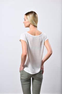 Blond girl, on white background, put her hands in back pockets