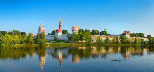 View on cloister monastery chapel walls, bell towers, pond with ducks. City park garden. Novodevichy Convent. Castle style monastery. Famous tourist sightseeing holidays vacations tours