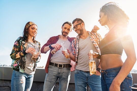 Joyful friends drinking alcohol on rooftop terrace