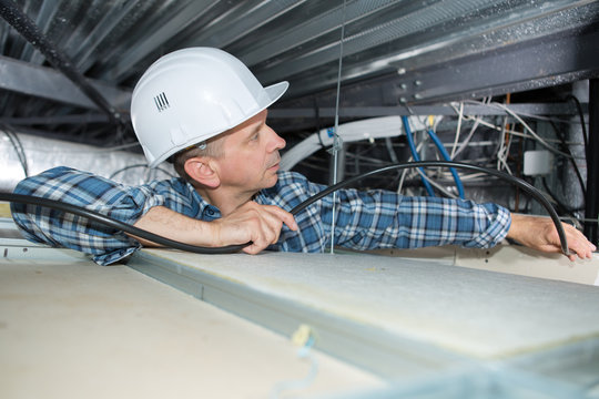Electrician installing cables into confined space