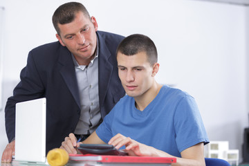 Older man helping younger man on computer