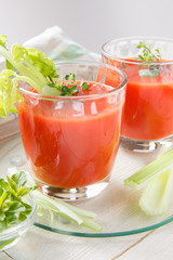 Two glasses of fresh tomato juice with thyme and celery.