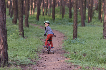 Child riding a bicycle. Kid in a helmet riding a bike in the forest. Beautiful baby. Authentic color.