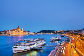 Naklejka premium Travel and european tourism concept. Parliament and riverside in Budapest Hungary with sightseeing ships during blue hour sunset