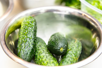 Fresh cucumbers lying with steel bowl.