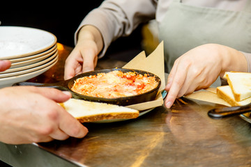 Cast iron black frying pan with scrambled eggs with tomatoes. A restaurant that guests don't see.