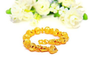 Gold bracelet 96.5 percent Thai gold grade with flowers and unique gold heart pendant isolated on white background