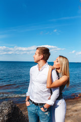 Happy couple on sea background. Happy young couple laughing and hugging on the beach