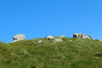 Limestone rock blocks in a mountain field covered by grass