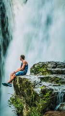 Fototapeta premium Man sitting in Front of Tegenungan Waterfall near Ubud in Bali, Indonesia