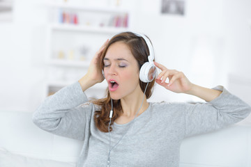 Naklejka premium Young woman singing along to music on headphones