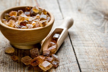 brown lumps of sugar in bowls on wooden table background