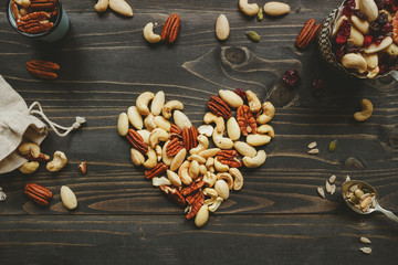 Nuts mix in heart shape on the wooden table. Nuts mix with seeds and dried fruits on the wooden table