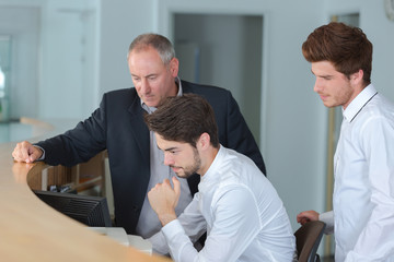 Fototapeta premium Men behind reception desk looking at computer