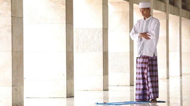  
Young religious person praying alone in the mosque with poses of standing, bowing, prostration, sitting, second prostration, second sitting, and greetings or taslim
