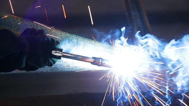 Worker welding a metal construction in a factory.