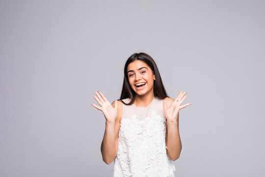 Young beautiful woman with facial expression of surprise standing over gray background.