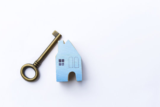 Blue wooden miniature house and antique key on white background