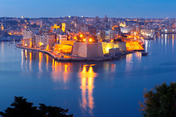 Fototapeta na wymiar Skyline aerial view of ancient Fort Saint Michael of Senglea peninsula and the Grand Harbor as seen from Valletta during morning blue hour, Malta.