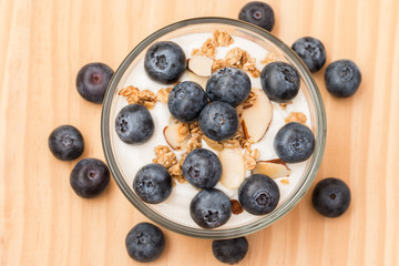 Yogurt with granola and organic blueberries in glass bow.