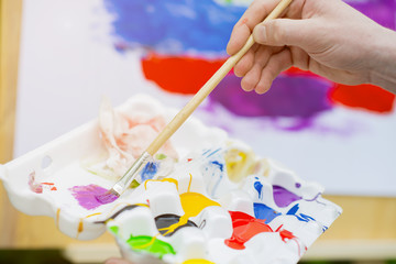 Hand of an artist painting a colorful picture
