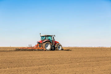 Obraz premium Farmer in tractor preparing land with seedbed cultivator as part of pre seeding activities in early spring season of agricultural works at farmlands.