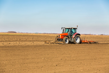 Obraz premium Farmer in tractor preparing land with seedbed cultivator as part of pre seeding activities in early spring season of agricultural works at farmlands.