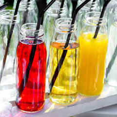 Colorful cocktails or juices, shots with straws in small glass bottles .