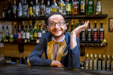 A cheerful bartender at the bar in a suit with a butterfly with a dollar sign