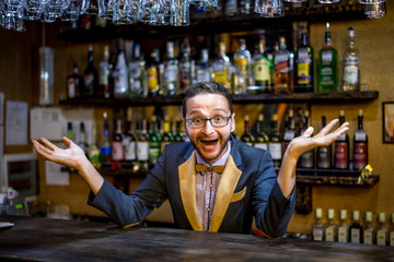 A cheerful bartender at the bar in a suit with a butterfly with a dollar sign