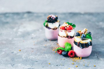 Assortment of creamy gourmet strawberry desserts layered in decorative patterns in individual glass containers